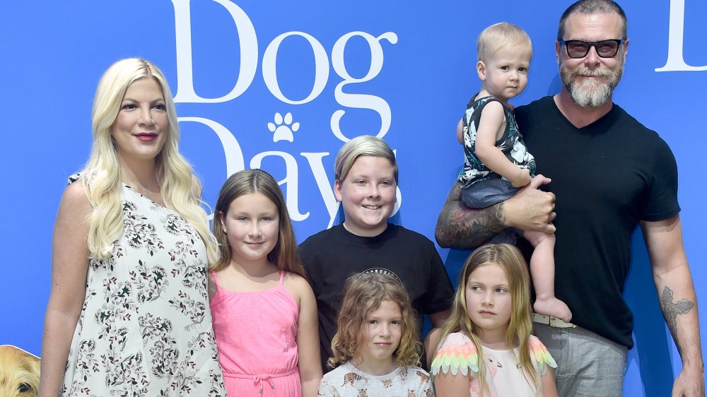 Tori Spelling in a white floral dress, Dean McDermott in a black t-shirt, posing with their kids