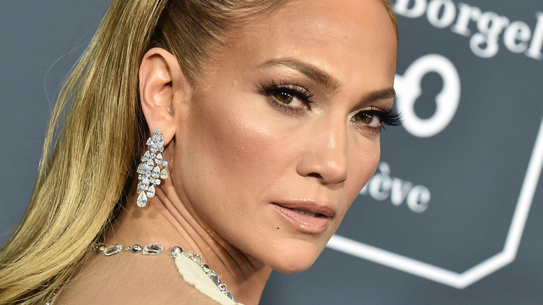 Jennifer Lopez si guarda alle spalle, con orecchini di diamanti