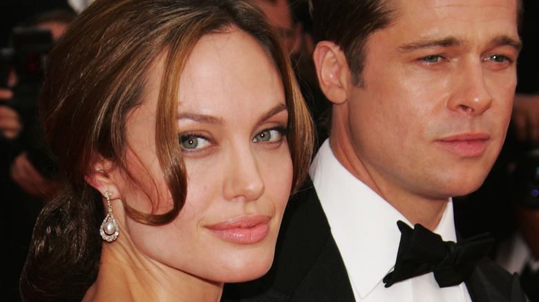Angelina Jolie sorride alla telecamera Brad Pitt guarda avanti