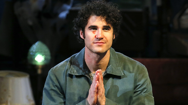 Darren Criss con le mani in preghiera, guardando